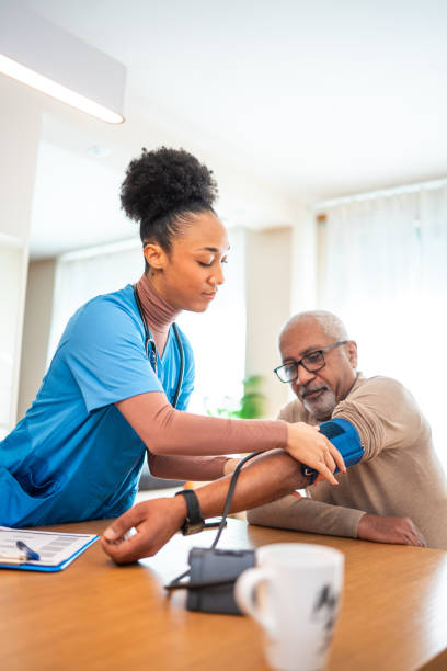Caregiver checking a senior client's blood pressure at home